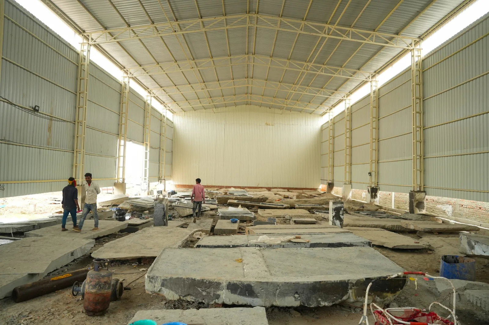 Stone fabrication floor with workers and large stone slabs under a covered structure