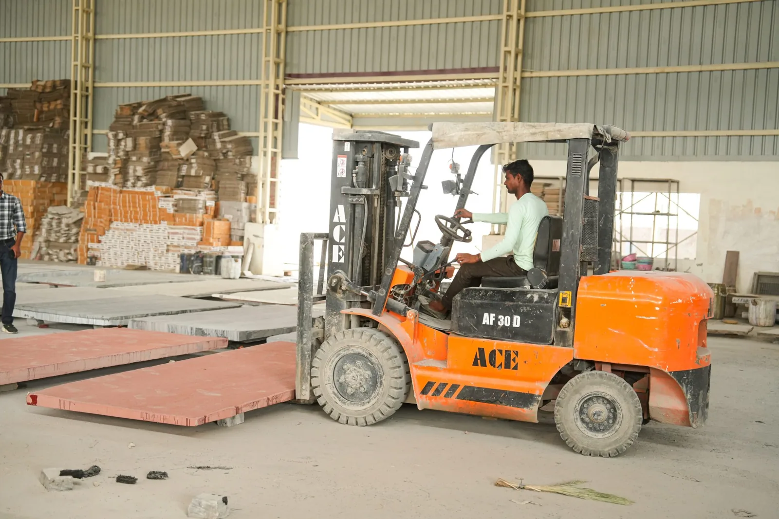 Forklift moving a large stone slab inside a fabrication facility